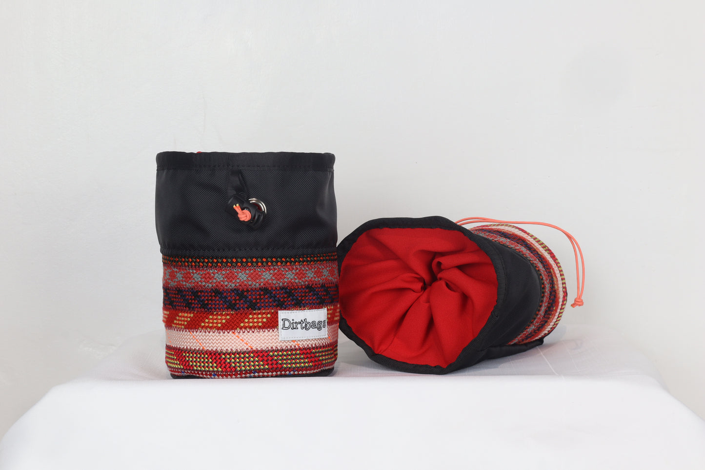 Two fabric bags, one black and one red with patterned base, on a white surface.