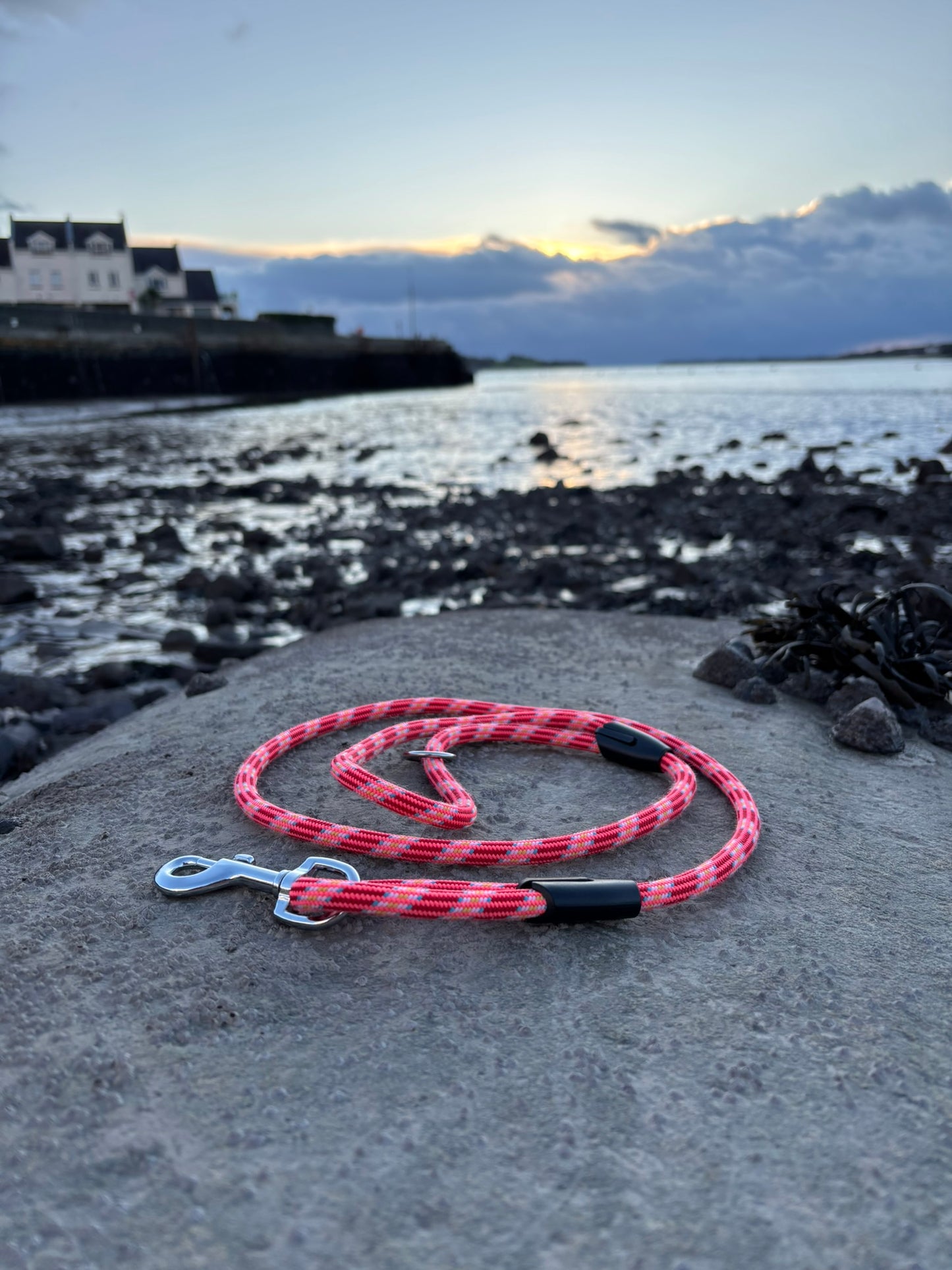 Upcycled Pink and black braided dog lead out of climbing rope on a concrete surface on the North Wales coast in the background
