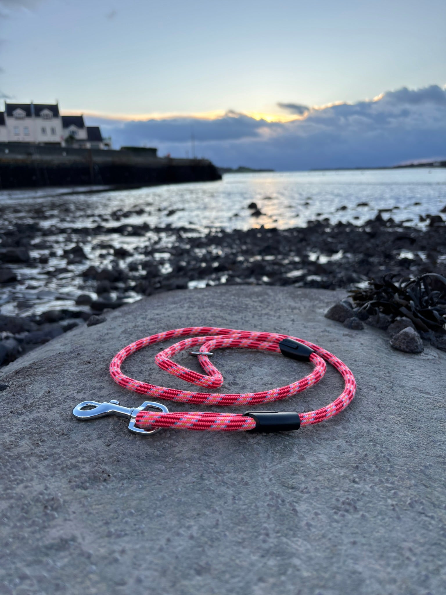 Upcycled Pink and black braided dog lead out of climbing rope on a concrete surface on the North Wales coast in the background